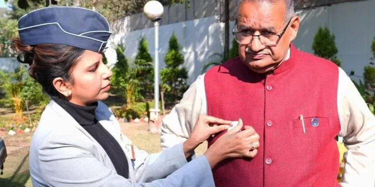 Dev Bhoomi Samiksha सशस्त्र सेना झंडा दिवस के अवसर पर सैनिक कल्याण मंत्री गणेश जोशी को फ्लैग लगाते विभाग के अधिकारी -